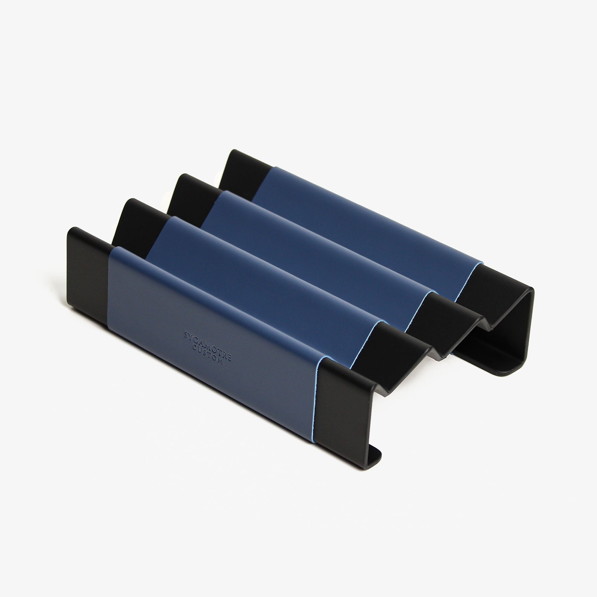 Top view of the ocean-blue leather and aluminum pen tray on a wooden desk