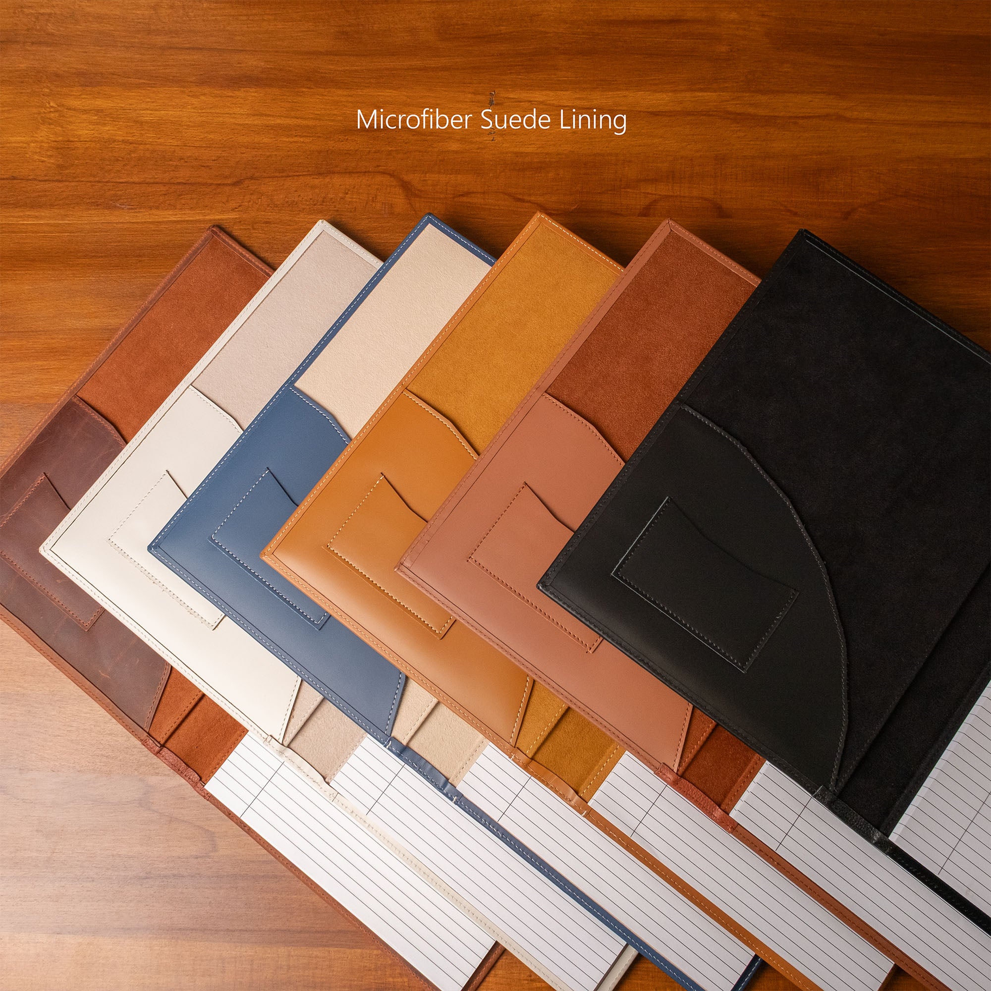 Collection of leather-bound notebooks in various colors on a wooden surface.