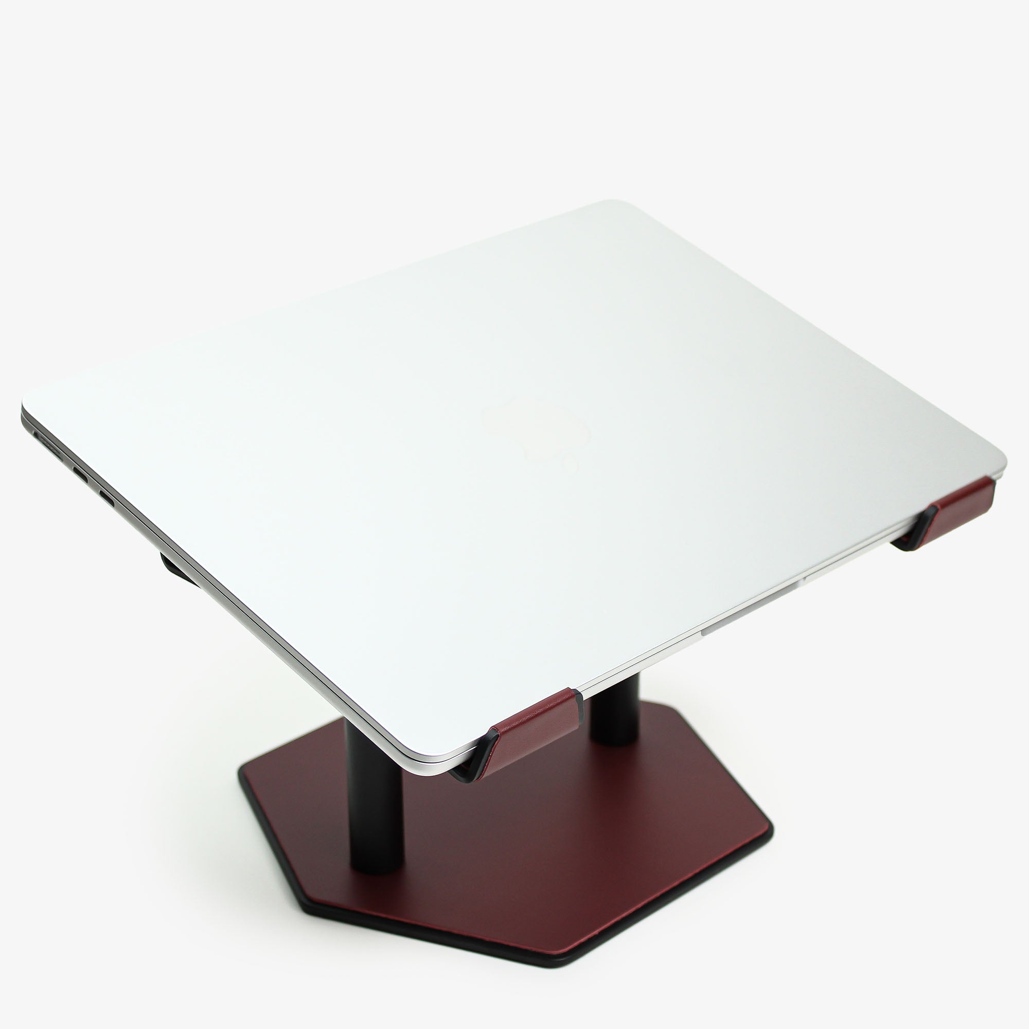 Side angle showing the ergonomic tilt of the burgundy laptop stand with macbook
