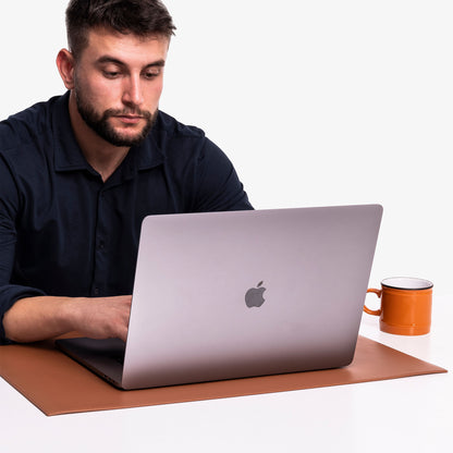 person working on brown leather desk pad